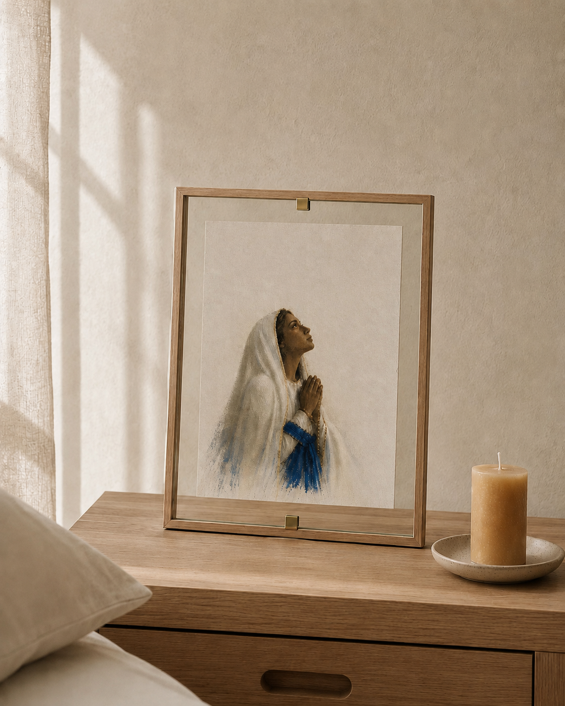 Nossa Senhora de Lourdes em moldura transparente apoiada sobre móvel de madeira, ao lado de uma vela